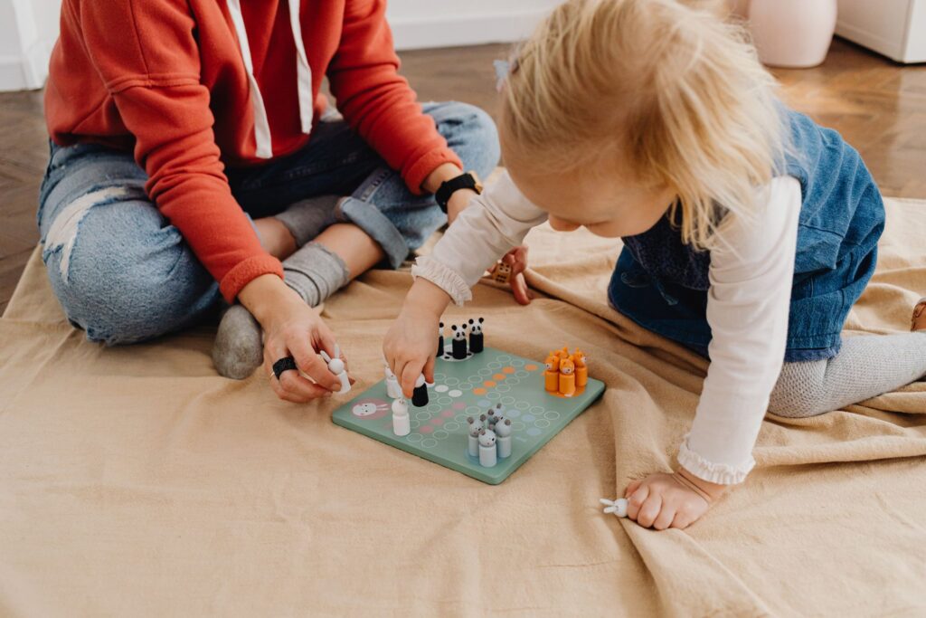 Mama su dukra namuose žaidžia spalvingą „Ludo“ stalo žaidimą